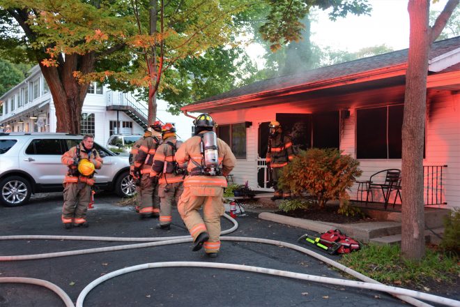 Firefighters entering and standing in front of single story home
