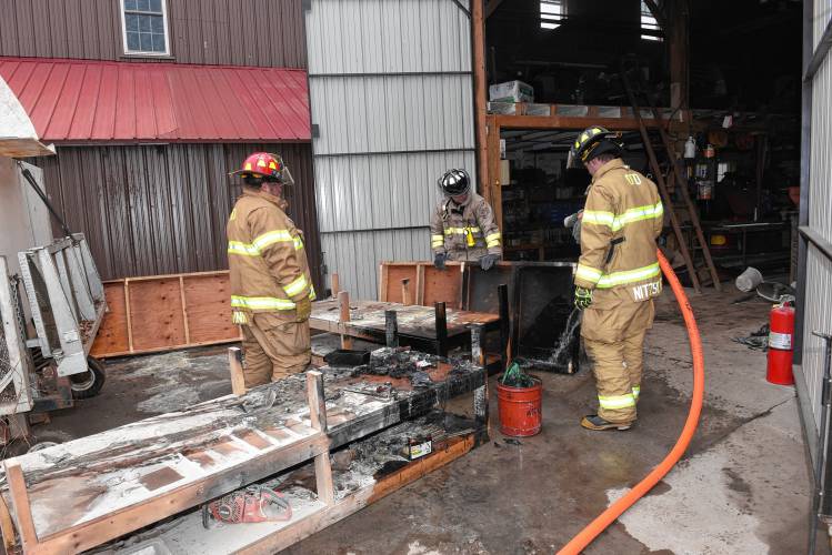 firefighters remove burnt materials from a workshop