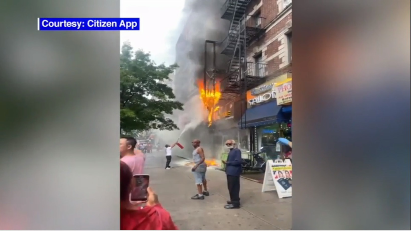 Fire shown on exterior of liquor store with citizen using fire extinguisher